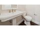 Powder room with pedestal sink, and matching white toilet set against neutral walls and wood-look flooring at 13200 Faro Ct # 44, Winter Garden, FL 34787