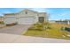 Two-car garage, landscaped yard, and light-green exterior at 1987 Key Bay Trl, Kissimmee, FL 34747