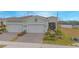 Two-car garage, landscaped yard, and light-green exterior at 1987 Key Bay Trl, Kissimmee, FL 34747