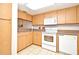 Kitchen with light wood cabinets, white appliances, and tile flooring at 669 Grenadine Ct # S, Winter Park, FL 32792