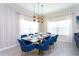 Elegant dining room with glass table and blue velvet chairs at 1176 Challenge Dr, Davenport, FL 33896