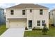 Two-story house with beige exterior, two-car garage, and landscaping at 1177 Alstonia Ln, Mount Dora, FL 32757