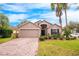 Tan house with a brick driveway, landscaping, and palm trees at 12002 Great Commission Way, Orlando, FL 32832