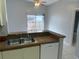 Kitchen view of breakfast bar, stainless steel sink, and dishwasher, with sliding door to backyard patio at 1332 Azalea Way, Winter Garden, FL 34787