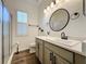 Bathroom features a walk-in shower, window, and updated vanity with a round mirror at 190 Crepe Myrtle Dr, Groveland, FL 34736