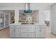 Kitchen island with gray cabinets, white countertops, and a view into the living room with a fireplace at 417 Main Trl, Ormond Beach, FL 32174