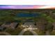 Stunning aerial view of a home with a circular driveway overlooking a serene lake and lush green golf course at 8513 Bay Hill Blvd, Orlando, FL 32819