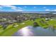 Panoramic aerial view showcasing a home nestled on a golf course near a shimmering lake, all under a clear blue sky at 8513 Bay Hill Blvd, Orlando, FL 32819
