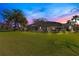 Spacious backyard with a screened-in pool area and lush green lawn at sunset at 8513 Bay Hill Blvd, Orlando, FL 32819