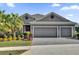 Gray house with three-car garage, palm trees, and landscaped yard at 943 Gracie Ridge St, Clermont, FL 34715