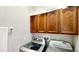 Convenient laundry room features silver washer and dryer with wooden cabinets for storage at 1855 Sugar Cove Ct, Ocoee, FL 34761