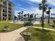 Relaxing green space, walking path, and pool area with lounge chairs and umbrellas at condo at 2626 S Atlantic Ave # 102, Daytona Beach Shores, FL 32118