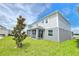 The home's exterior displays light gray siding and a covered porch area with a manicured lawn and a young tree at 2678 Great Heron Ave, St Cloud, FL 34773