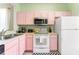 Kitchen boasts pink cabinets, stainless steel appliances, and a checkerboard floor at 2735 Calabria N Ave, Davenport, FL 33897