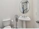 Powder room with pedestal sink, toilet, and oval mirror at 8229 Tivoli Dr, Orlando, FL 32836