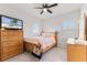 Cozy bedroom with wood dresser, ceiling fan, and striped bedding at 1861 Goblet Cove St, Kissimmee, FL 34746