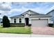 Charming home with manicured lawn, lush landscaping, and a brick paver driveway leading to a two-car garage at 3333 Wauseon Dr, St Cloud, FL 34772