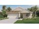 One-story home with a two-car garage, light beige siding, and landscaping at 5808 Galloping Dr, Apopka, FL 32712