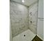 Modern shower with marble-look tiles and pebble floor at 1304 Hillsborough Ct, Kissimmee, FL 34759