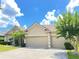 Tan three-car garage home with lush landscaping at 142 Winghurst Blvd, Orlando, FL 32828