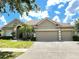 Tan two-story house with three-car garage, palm trees, and lush lawn at 142 Winghurst Blvd, Orlando, FL 32828