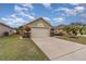 Tan house with a two-car garage and lush green landscaping at 2368 Monaco Cove Cir, Orlando, FL 32825