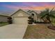 Tan house with a two-car garage, landscaping, and a palm tree at 2368 Monaco Cove Cir, Orlando, FL 32825