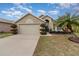 Two-car garage, tan house with landscaping and palm tree at 2368 Monaco Cove Cir, Orlando, FL 32825