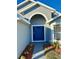 Blue front door with a walkway and landscaping at 2413 Rock Ct, Poinciana, FL 34759