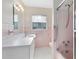 Retro bathroom featuring pink tiling, shower stall, and white vanity with ample counter space at 280 E Constance Rd, Debary, FL 32713