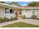 Welcoming front entrance with a bright yellow door, landscaping, and a curved walkway at 332 Lake Winnemissett Dr, Deland, FL 32724