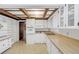 White kitchen with wood beam ceiling, tiled floor and modern appliances at 5217 N Apopka Vineland Rd, Orlando, FL 32818