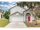 Two-story house with a gray facade, red door, and a two-car garage at 587 Bluff Pass Dr, Eustis, FL 32726