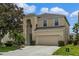 Two-story house with beige exterior, a large garage, and lush landscaping at 7773 Basnett Cir, Kissimmee, FL 34747