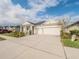 Cream-colored house with a three-car garage and manicured landscaping at 17791 Passionflower Cir, Clermont, FL 34714