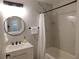 Bathroom with marble tile, modern vanity, round mirror, and bathtub with black hardware at 2592 Grassy Point Dr # 106, Lake Mary, FL 32746