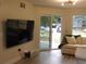 Living room with sliding glass door leading to patio and large TV at 2592 Grassy Point Dr # 106, Lake Mary, FL 32746