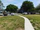 Exterior view of a parking area with neatly parked cars and a sidewalk leading towards the building entrance at 2592 Grassy Point Dr # 106, Lake Mary, FL 32746