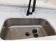 Close-up of stainless steel kitchen sink with modern black faucet and white countertops at 2592 Grassy Point Dr # 106, Lake Mary, FL 32746