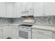 White kitchen with a mosaic backsplash and stainless steel appliances at 597 Lost Shaker Way, Daytona Beach, FL 32124