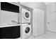 Laundry room with stacked washer and dryer, black cabinets, and white door at 7615 Bay Port Rd # 36, Orlando, FL 32819