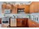 Close-up of a kitchen with stainless steel appliances, cherry wood cabinets, granite countertops, and tile backsplash at 150 E Robinson St # 3104, Orlando, FL 32801