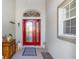 Front entry with red door, decorative rug and wooden cabinet at 17478 Se 115Th Terrace Rd, Summerfield, FL 34491