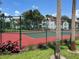 Community tennis court with red surface, green fence, and lush landscaping at 11538 Westwood Blvd # 226, Orlando, FL 32821