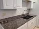 A kitchen sink with granite countertops and stainless steel faucet under white cabinetry at 155 N Pearl Lake Cswy # 200, Altamonte Springs, FL 32714