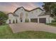 Lovely two-story home with a brick driveway and tile roof, shown at dusk at 408 Chelsea Ave, Davenport, FL 33837