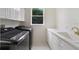 Laundry room with a utility sink, modern appliances, white cabinets, and a view out to the backyard at 408 Chelsea Ave, Davenport, FL 33837