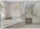 Luxurious main bathroom featuring white marble accents, soaking tub, and arched windows with plantation shutters at 408 Chelsea Ave, Davenport, FL 33837