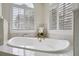 Beautiful soaking tub with gold fixtures, marble surround, and arched window providing natural light in bathroom at 408 Chelsea Ave, Davenport, FL 33837