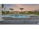 Luxury pool and spa at sunset with a decorative fountain feature and brick pavers for stylish outdoor living at 408 Chelsea Ave, Davenport, FL 33837